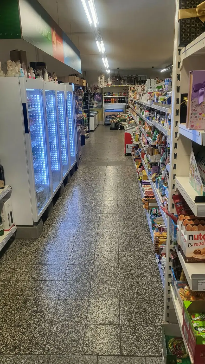 An aisle with refrigerated display cabinets and shelves stocked with food