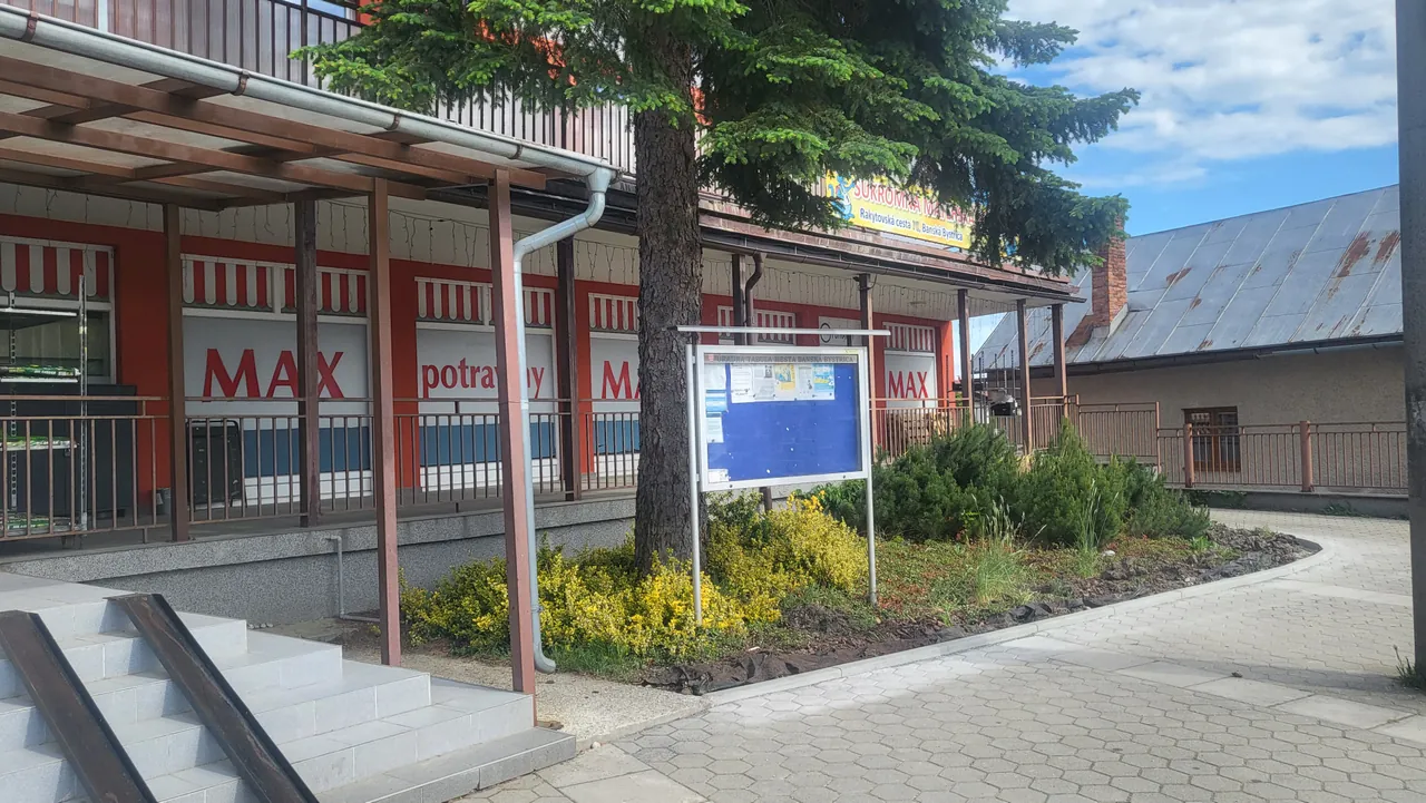 Pohľad na úradnú tabuľu mestskej časti Rakytovce — modrá vitrína na kovovej konštrukcii pred budovou na Rakytovskej ceste